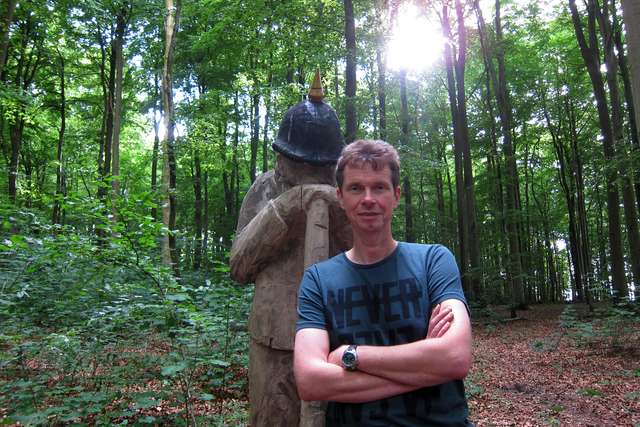 Helmut im Wald von Sottrupskov vor Holzfigur